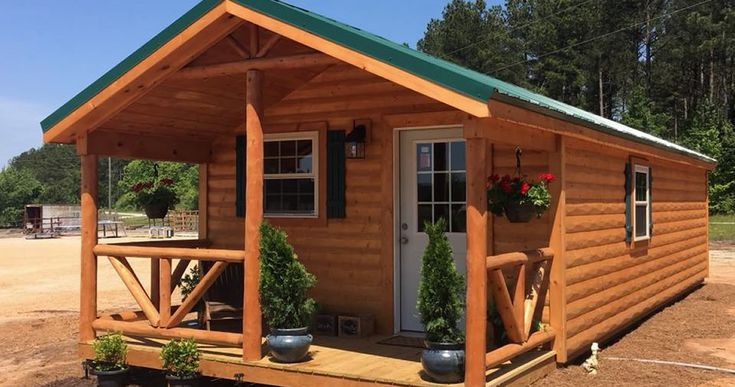 a small wooden cabin sitting on top of a dirt field next to a green roof