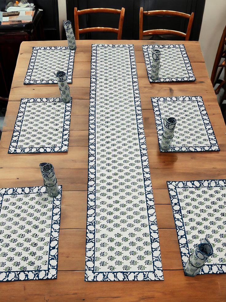 a wooden table topped with place mats covered in blue and white tile