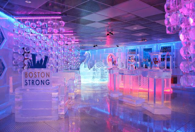 an ice bar is lit up with neon lights and snow sculptures on the walls, along with signs that read boston strong