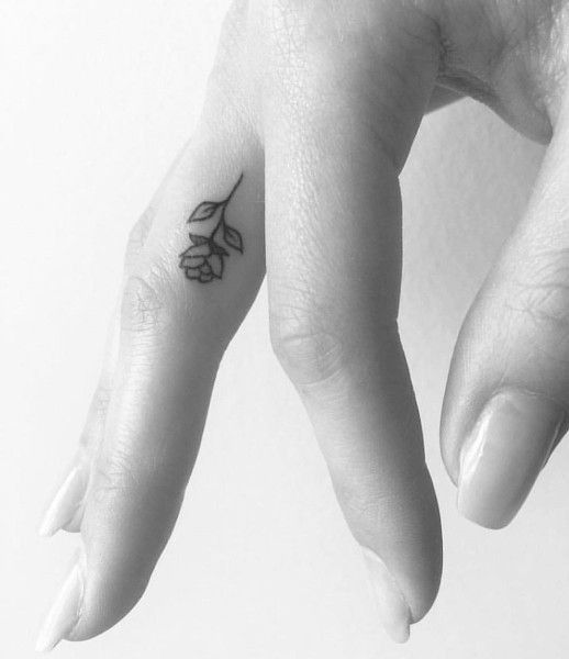 a person's hand with a small flower tattoo on their left thumb and finger