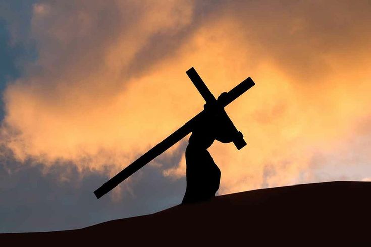 the silhouette of a person carrying a cross against a cloudy sky with clouds in the background