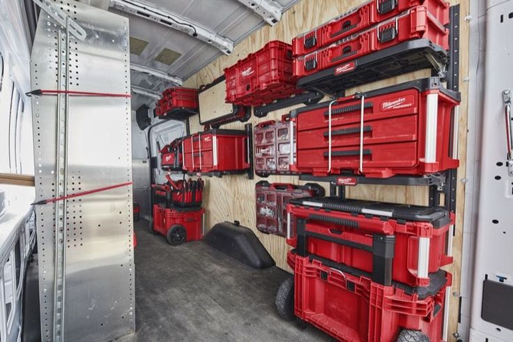 the inside of a truck with many red tool boxes on it's wall and shelves