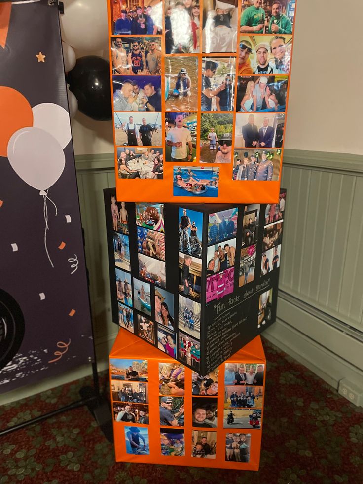 an orange display case with pictures on it and balloons hanging from the top, in front of a wall