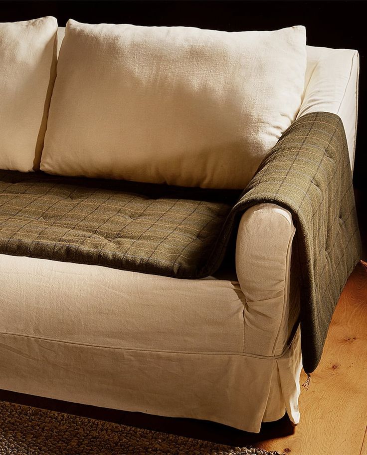 a couch with two pillows on top of it in front of a wooden floor and wall