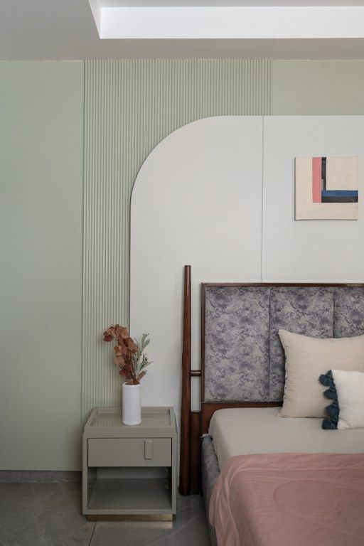 a bed sitting next to a night stand with flowers on top of it in a bedroom