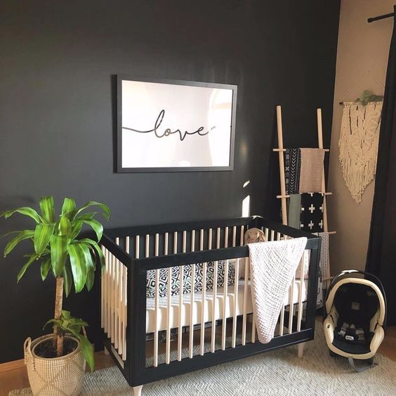 a baby crib in a room with a plant on the floor next to it