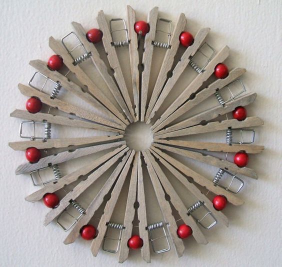 a clock made out of wooden pieces with red balls on it's sides and metal clips in the middle