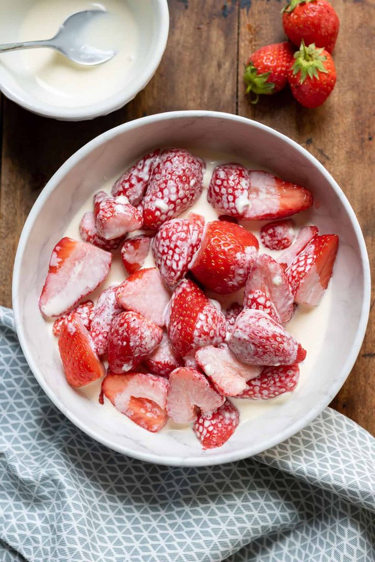 a bowl filled with strawberries and yogurt on top of a wooden table