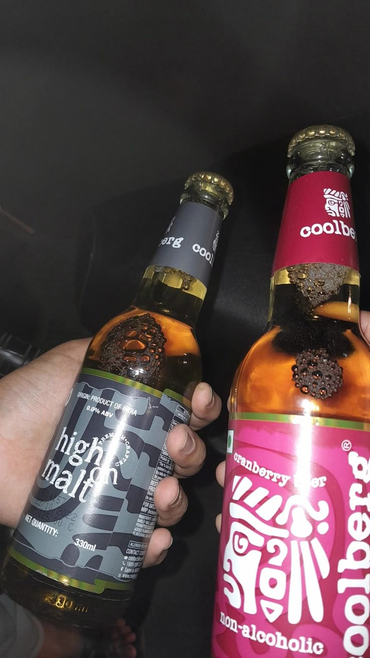 two bottles of beer are being held by someone