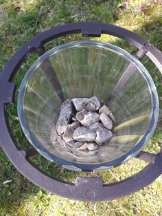 a glass bowl filled with rocks on top of grass