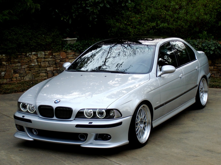 a silver car parked in front of a stone wall