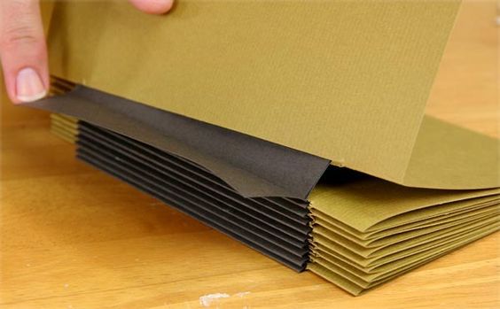 a stack of brown paper sitting on top of a wooden table next to a person's hand