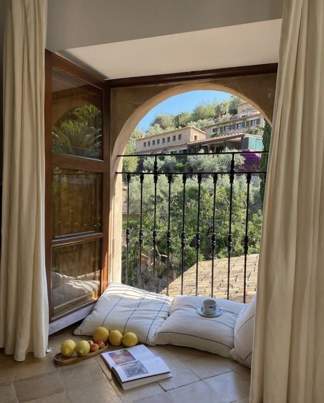 an open window with some fruit on the floor in front of it and a book