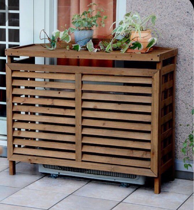 a wooden cabinet with plants in it sitting on the floor next to a patio door