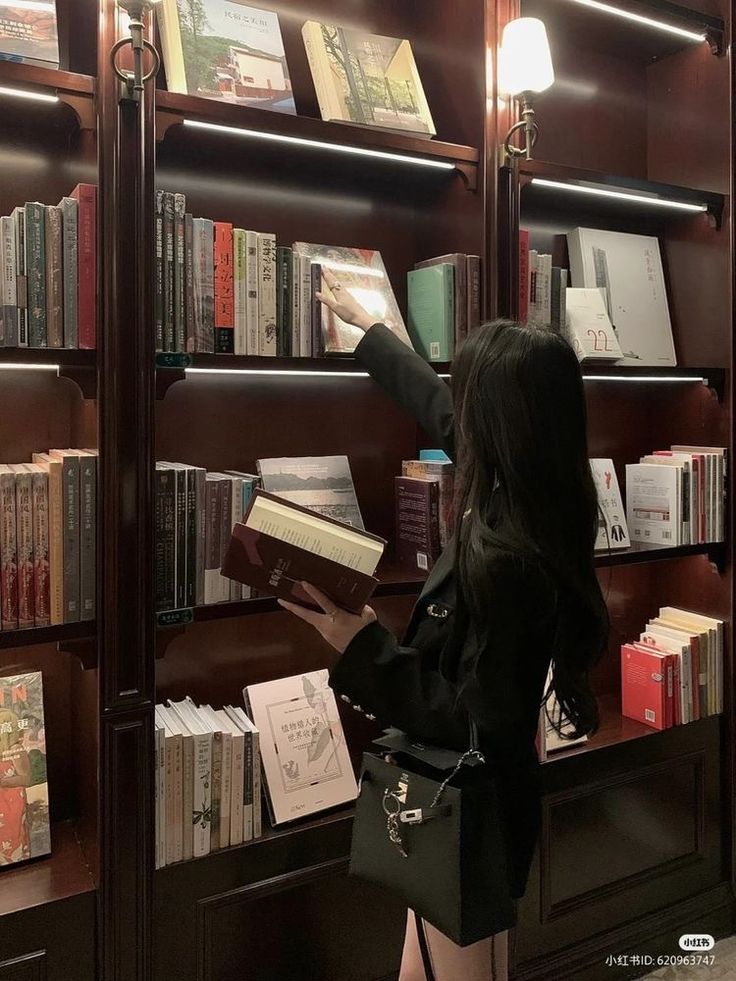 a woman standing in front of a book shelf filled with books