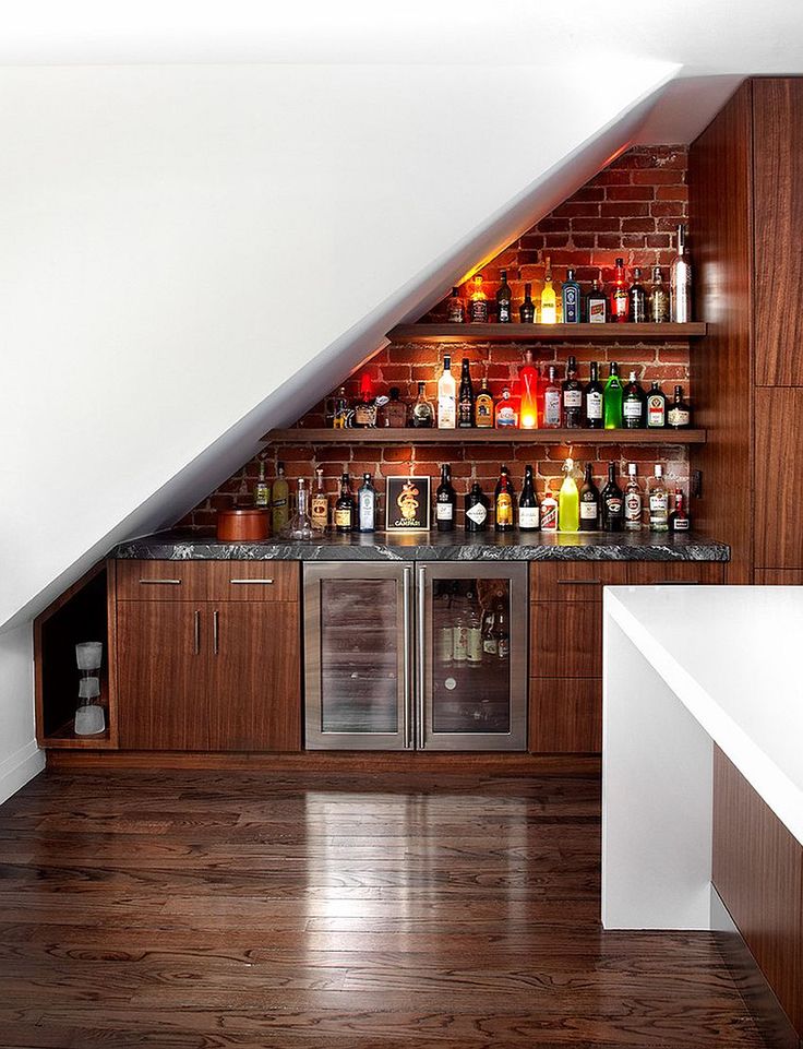 an attic bar with built in shelves and liquor bottles on the wall, along with other items