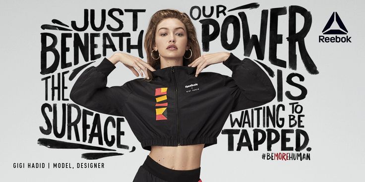 a woman posing in front of a wall with words on it and her hands behind her head