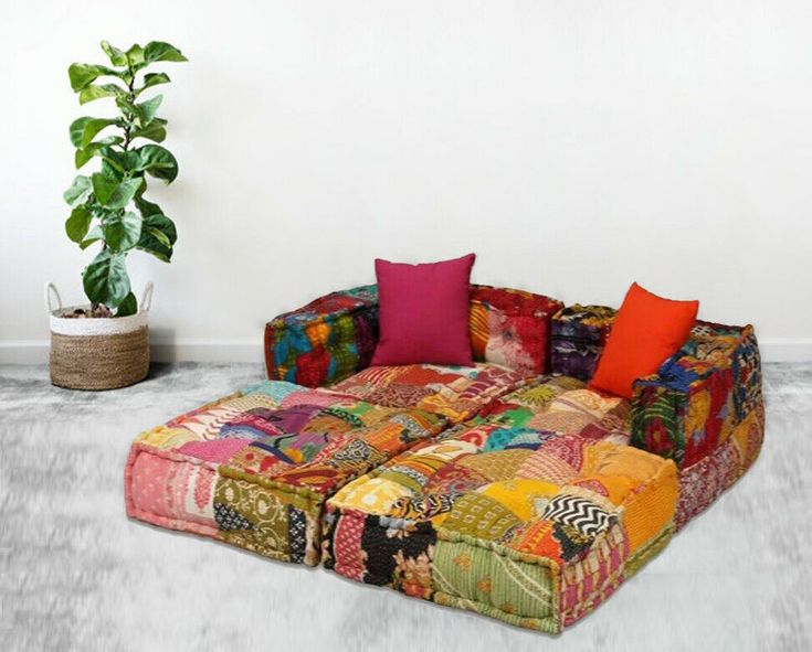 a multicolored patchwork couch sitting next to a potted plant on the floor