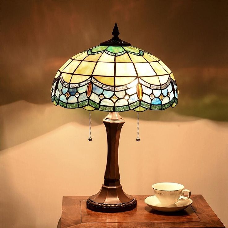 a lamp that is sitting on top of a table next to a cup and saucer