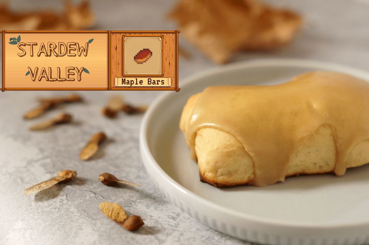 a white plate topped with a pastry covered in icing next to an autumn leaf