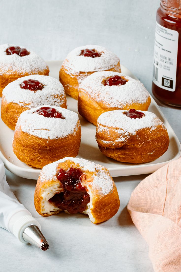 powdered sugar covered pastries on a plate with jam