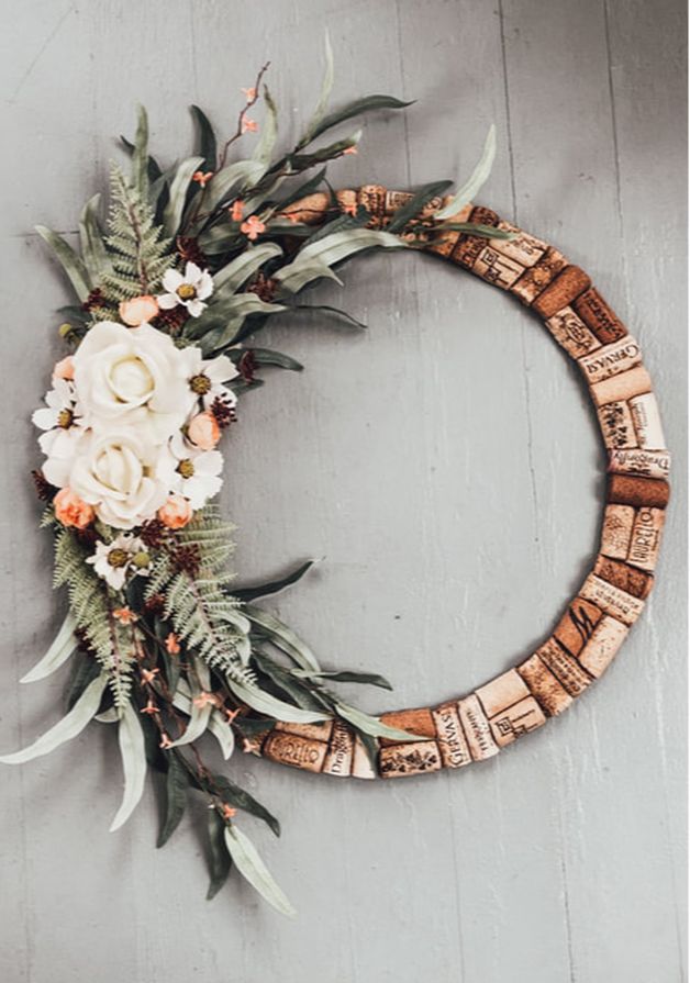 a wreath made out of wine corks with flowers and greenery on the side