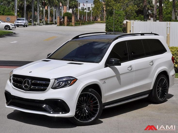 a white mercedes benz suv parked in front of a palm tree lined street with cars