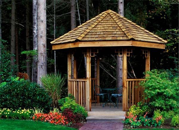 a wooden gazebo surrounded by flowers and trees