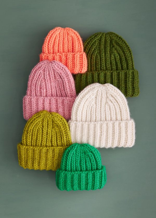 five knitted hats are shown in different colors and sizes, all on top of each other