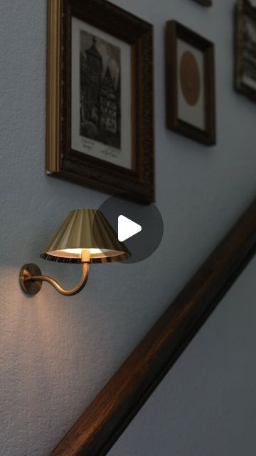 a lamp that is on the side of a wall next to some pictures and frames