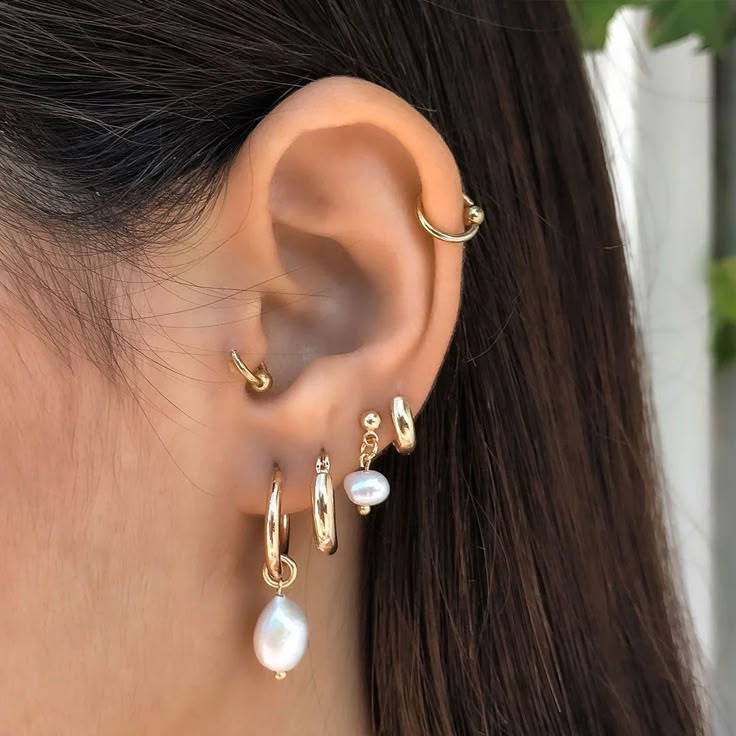 a close up of a woman's ear with pearl and gold hoops on it