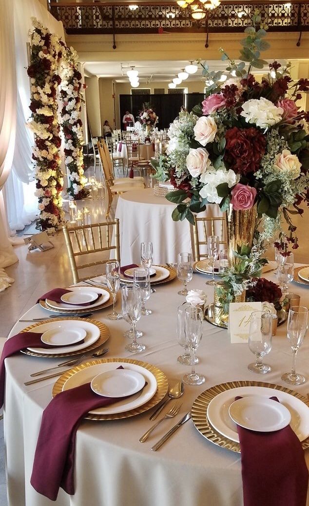 the table is set with white and gold plates, silverware, and flowers in vases