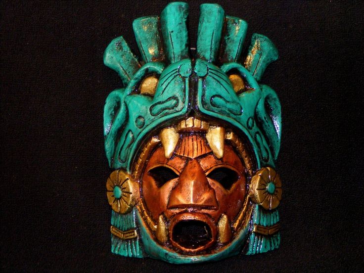 a wooden mask with green and gold designs on it's face, against a black background