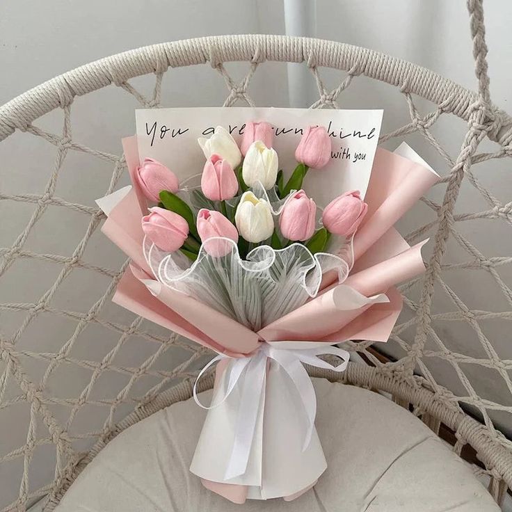 a bouquet of pink and white tulips on a chair