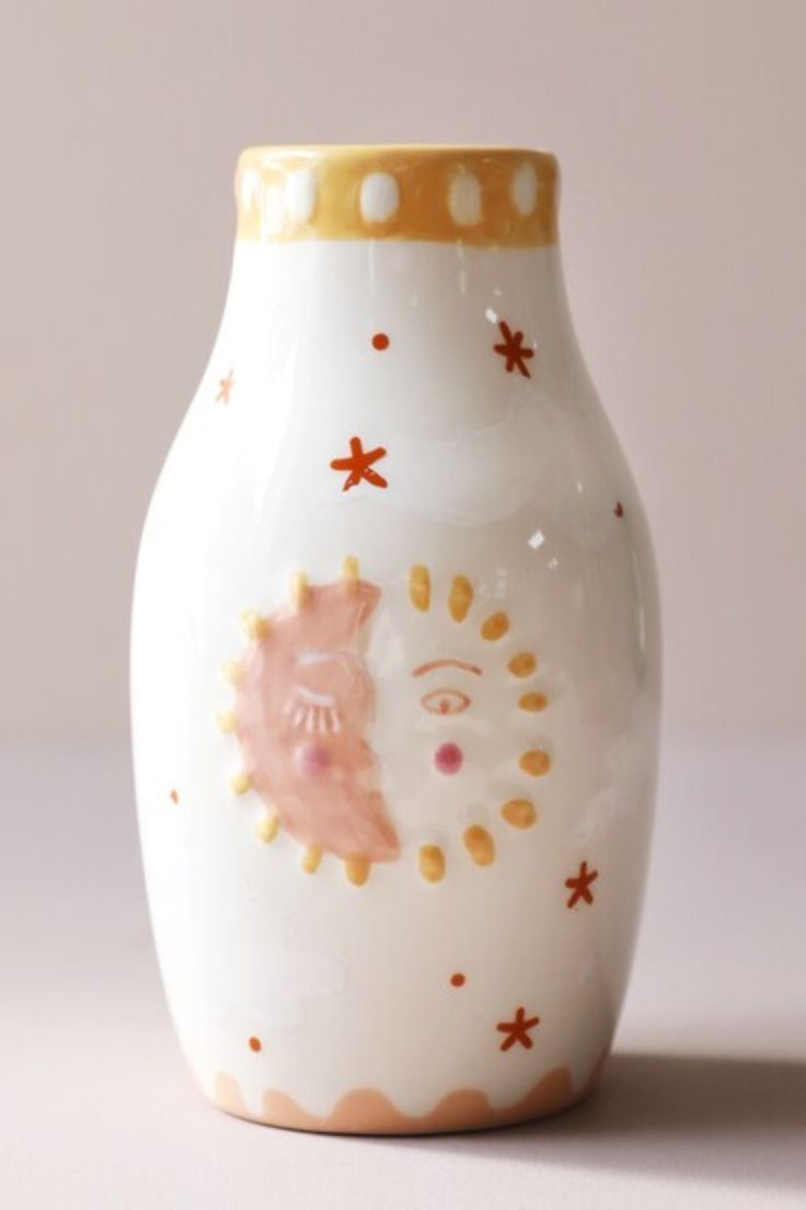 a white vase with pink and gold designs on it