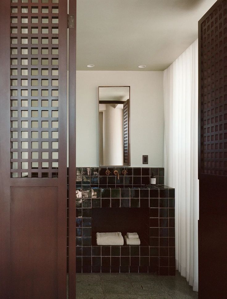 a bathroom with black tile and wooden doors