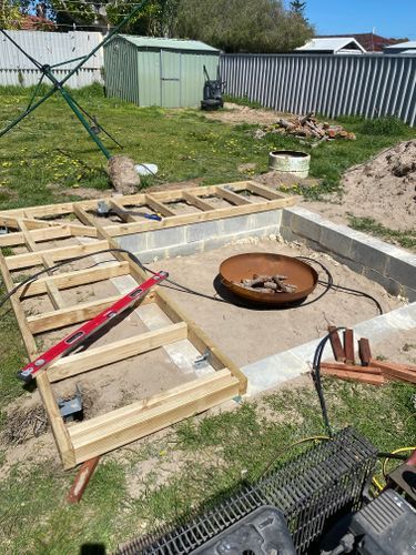 an outdoor fire pit is being built in the middle of a yard with construction materials around it