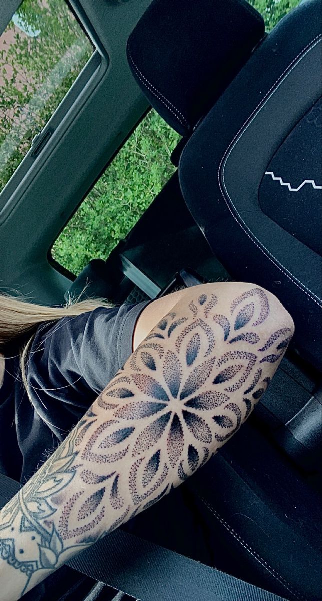 a woman sitting in the back seat of a car with a tattoo on her arm