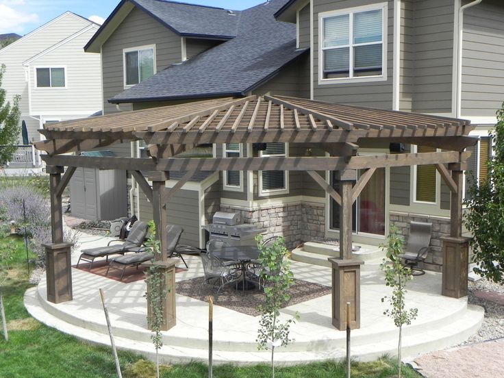 a covered patio with chairs and tables in front of a house