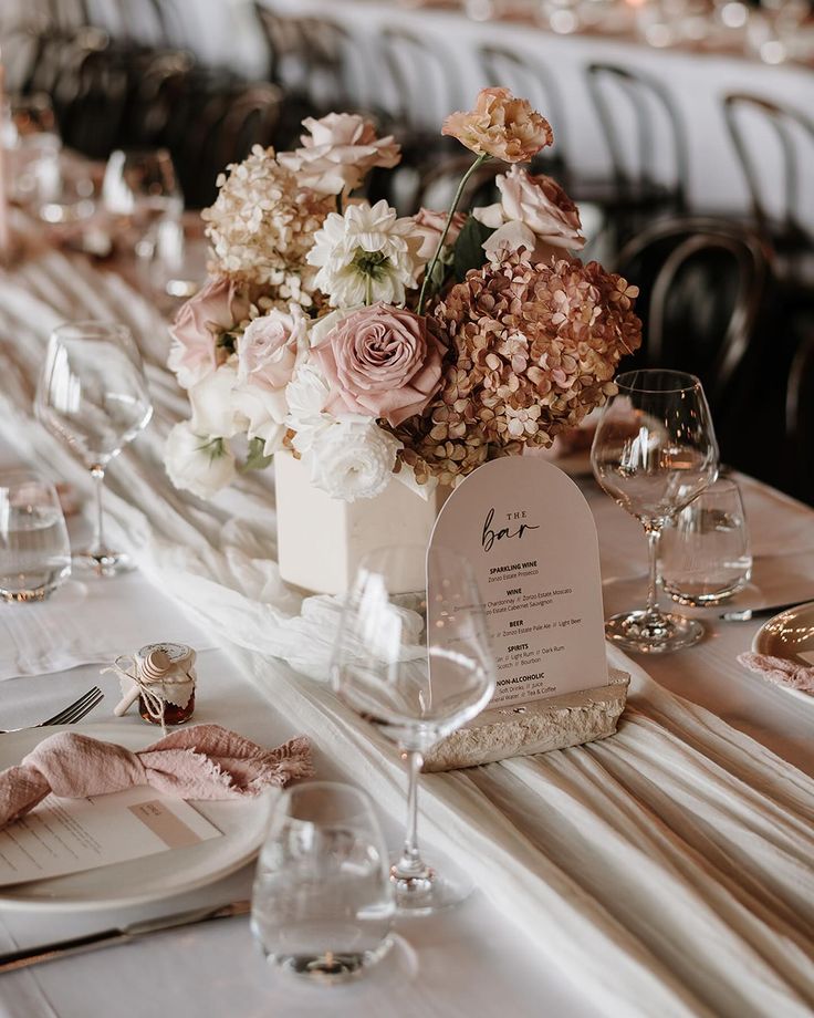 the table is set with flowers and place settings for guests to sit down at it