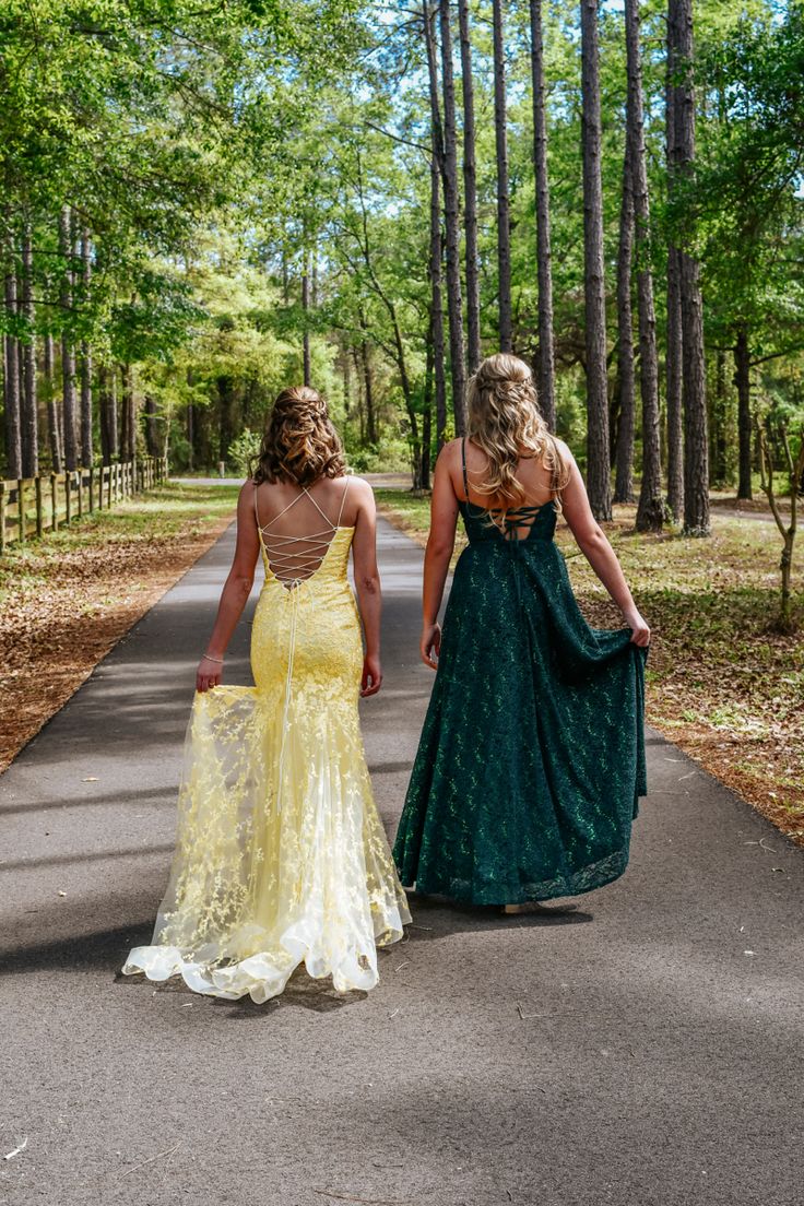 two women in dresses walking down a path