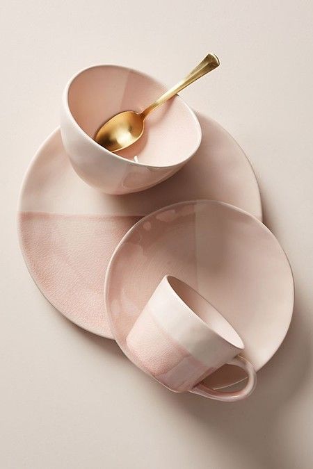 two white dishes with gold spoons and one pink bowl on top of each other