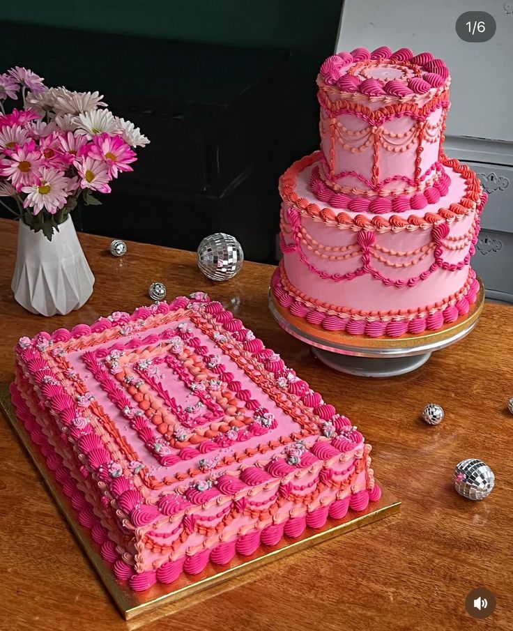 a pink cake sitting on top of a table next to a vase filled with flowers