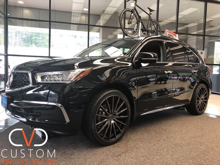 a black car with a bicycle on top of it's roof rack in a showroom