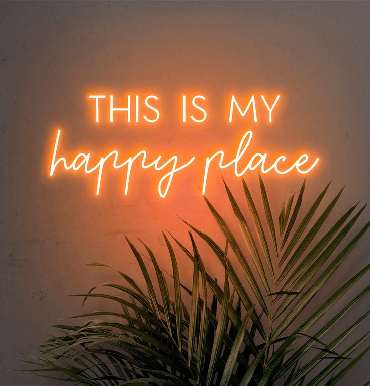 a neon sign that says, this is my happy place on the wall next to a potted plant