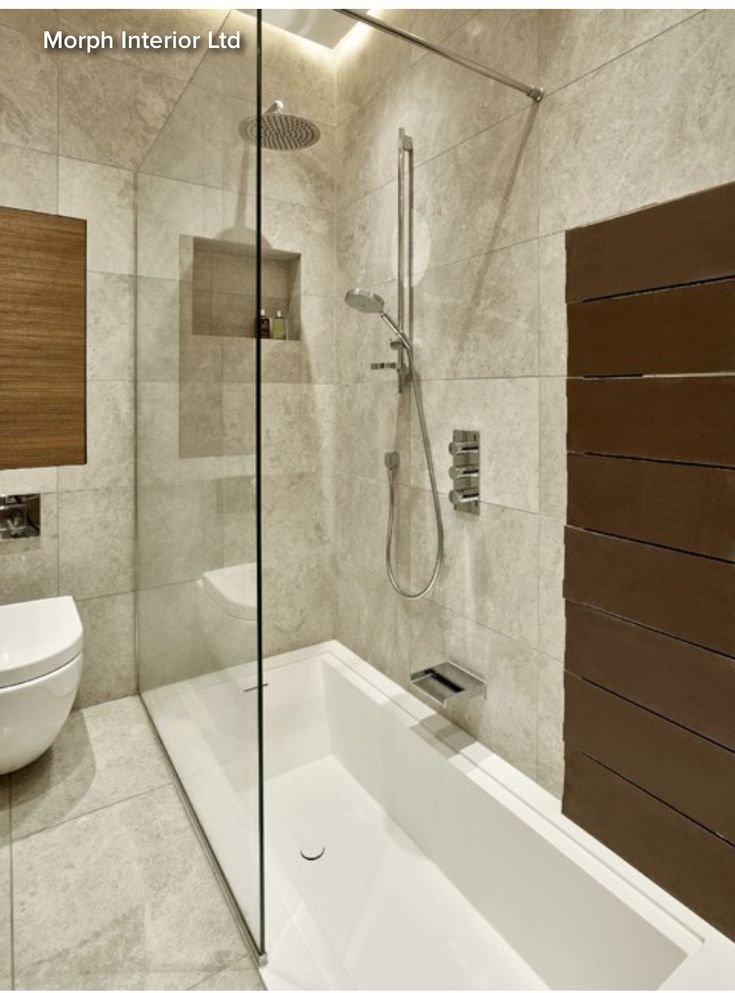 a bathroom with a tub, toilet and shower head mounted to the side of the wall