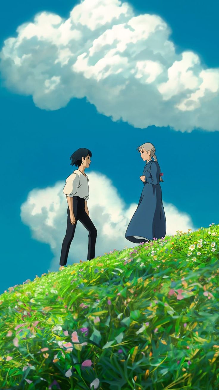 two people standing on top of a lush green hillside under a blue sky with clouds