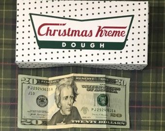 a dollar bill sitting in front of a christmas theme doughnut wrapper with the word,