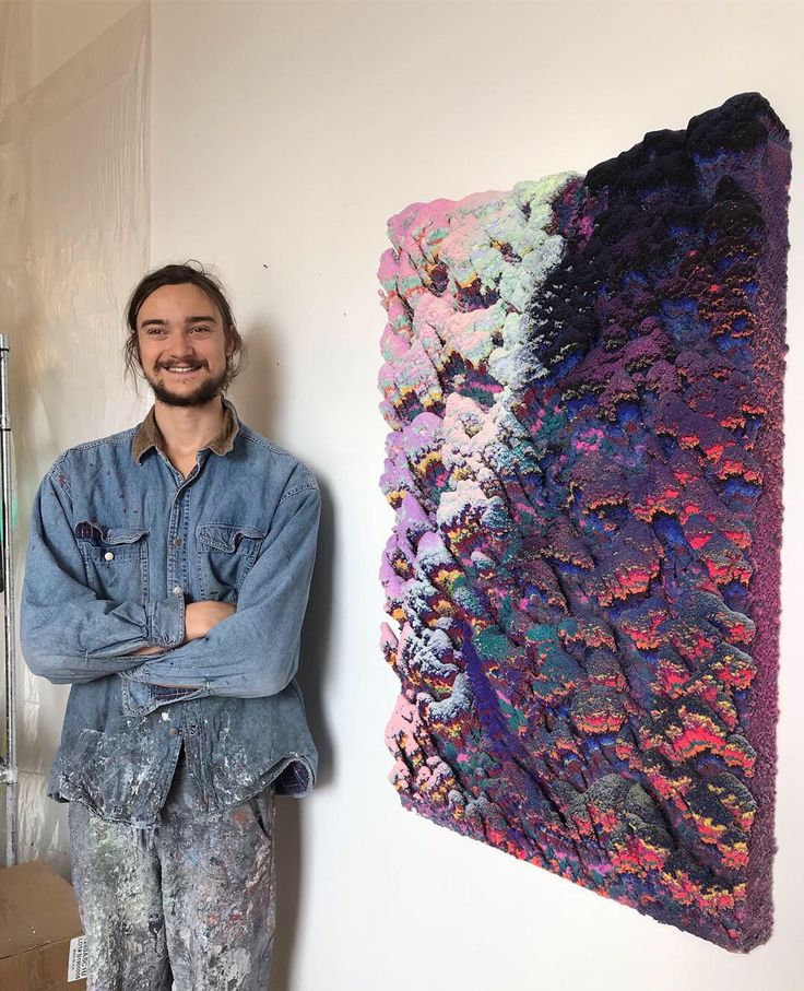 a man standing next to a painting on the wall