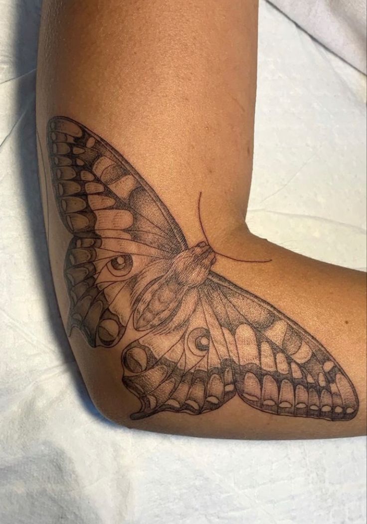 a close up of a butterfly tattoo on a person's arm and leg,